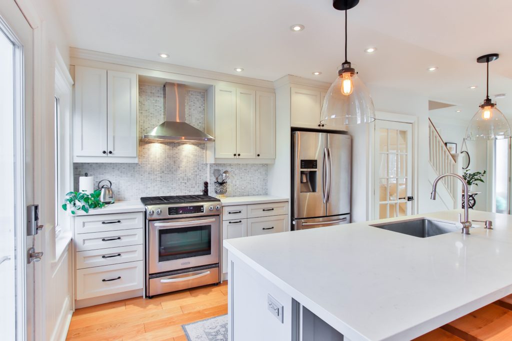 Kitchen remodel with glass pendant lights in black finish with island countertops of quartz. Kitchen renovation Houston.