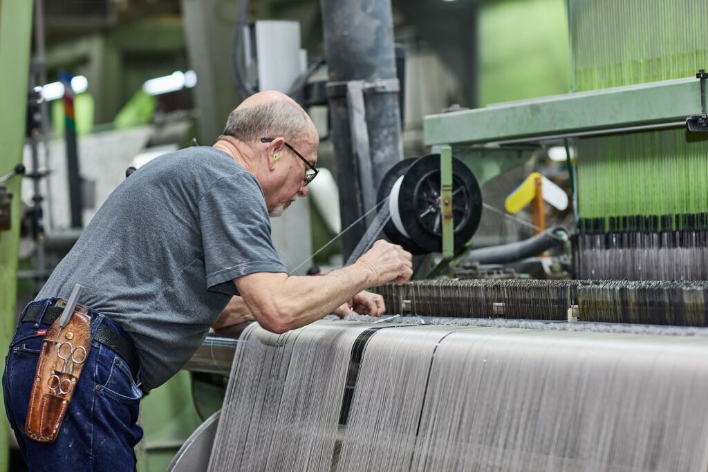 Fabric worker weaving revolution fabric on a weaving machine.