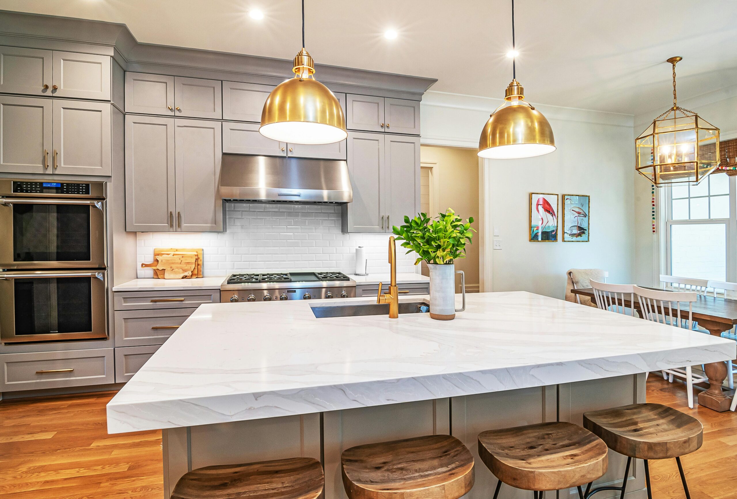 Kitchen remodel with gold pendant lighting and large island with quartz. Gray cabinets and tile backsplash. Kitchen Renovation Houston.