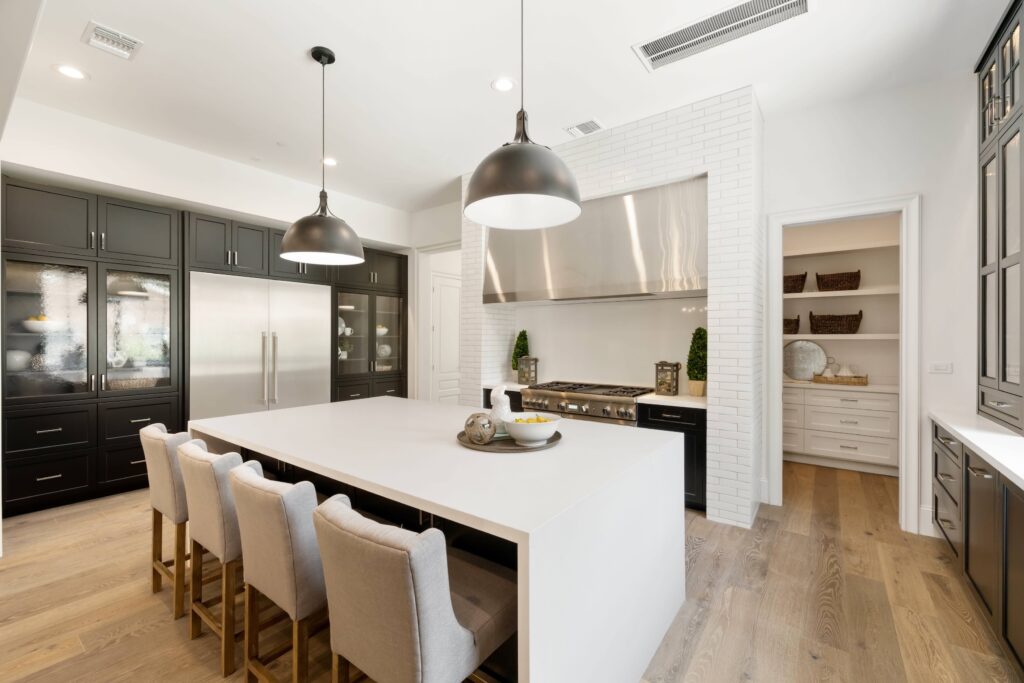 Modern kitchen remodel with with quartz countertops and dark cabinet finish. Large black pendants over island. Kitchen renovation Houston.
