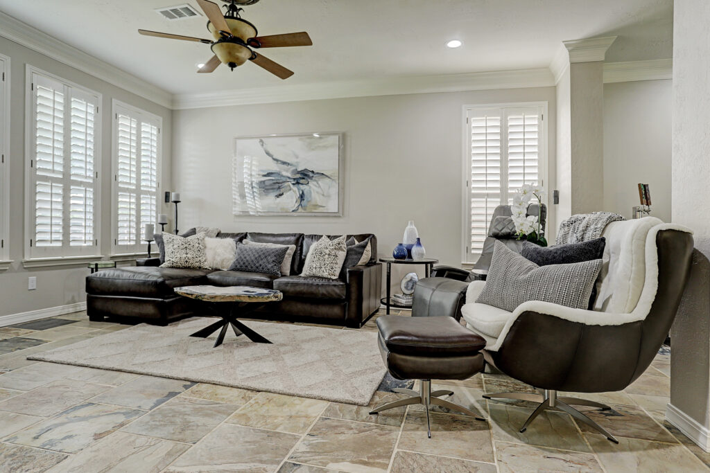 Photo of a family room designed by Two Sisters Designs with leather sofa and chair with textured rug.