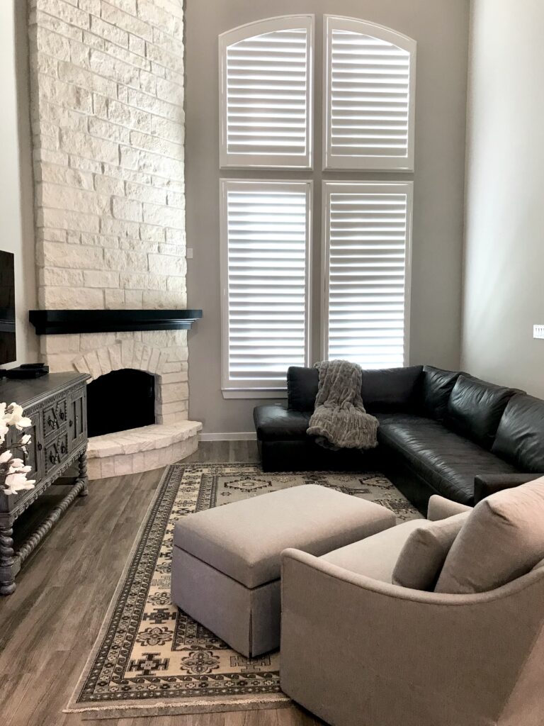 Shutters installed in a family room that has high windows with arches.