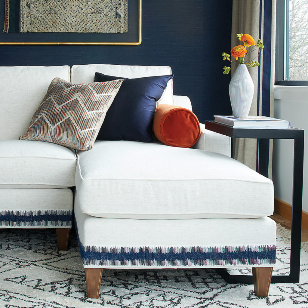 Sofa with revolution fabrics in creams with side table in a black finish and navy blue walls.