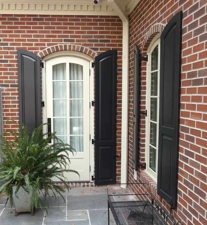 Raised Arched panel exterior shutters traditional style brick home in Houston.